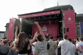 Menschen jubeln bei einem Open-Air-Konzert vor einer Bühne mit Sparkassen-Logo.