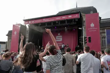 Menschen jubeln bei einem Open-Air-Konzert vor einer Bühne mit Sparkassen-Logo.