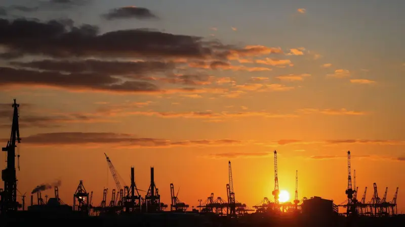 Silhouetten von Kränen im Hamburger Hafen bei Sonnenuntergang. Perfekt für die Pfingstferien in Hamburg.