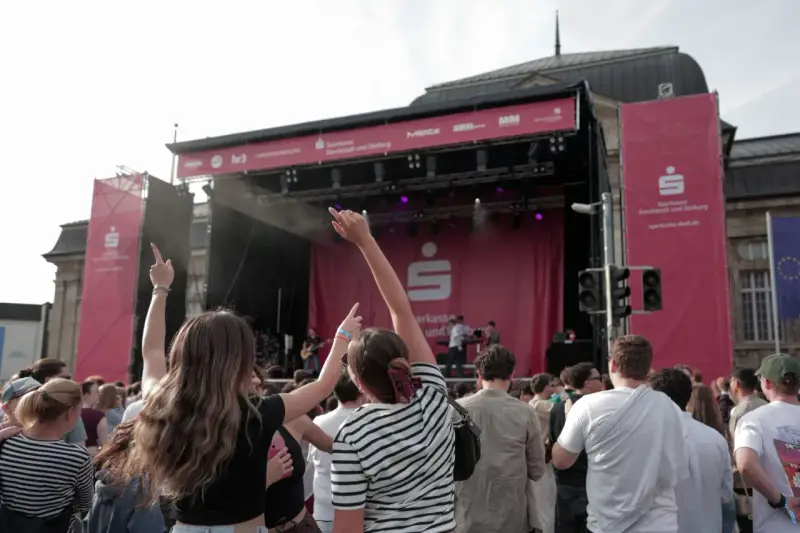 Menschen jubeln bei einem Open-Air-Konzert vor einer Bühne mit Sparkassen-Logo.